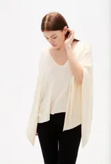 Poncho negro de tejido de punto con escote en V, diseño asimétrico y corte holgado.