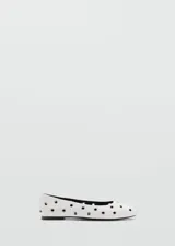 Zapato tipo bailarina color blanco con diseño troquelado de ojales metálicos, punta redonda y suela plana.
