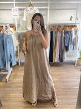 Vestido largo de lino color negro oscuro, con escote fruncido y tirantes finos ajustables. Presenta aberturas laterales en el ruedo.