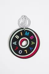 Llavero circular confeccionado en cuero y nylon de color negro, con el nombre de la marca bordado en letras de diversos colores. Incluye un cierre de mosquetón y una anilla metálica plateada para su sujeción.