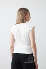 Top sin mangas de tejido acanalado color blanco, con cuello redondo, hombros definidos y detalle de frunce bajo el busto que aporta estructura.