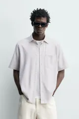 Camisa azul marino de corte regular fit confeccionada en tejido fluido de algodón y lino, con cuello solapa, manga corta, bolsillo aplicado en el pecho y cierre frontal con botones.