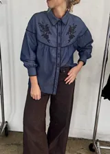 Camisa negra de manga larga con canesú estampado con diseño floral, cuello camisero y cierre frontal con botones.