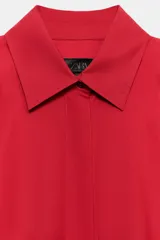 Camisa oversize verde de popelina de algodón, con cuello solapa, manga larga y cierre frontal con botones ocultos bajo solapa.