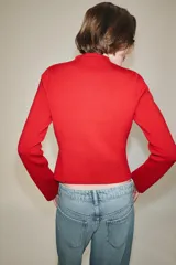Chaquetas de cuello redondo y manga larga, de color rojo. Cuenta con detalle de botones dorados frontales y en los puños, con cierre delantero con corchetes ocultos.