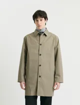 Gabardina clásica de corte recto, color beige, con cuello camisero, cierre frontal de botones y bolsillos laterales. Confeccionada en tejido técnico repelente al agua y al viento.