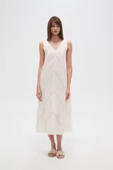Vestido midi de algodón color crudo, con cuello en V, sin mangas y diseño holgado. Presenta un delicado bordado lineal en forma de zigzag que recorre toda la prenda.