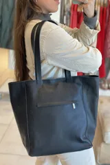 Bolso tipo tote de cuero negro con textura de pelo en el frente y cierres laterales.