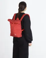 Mochila acolchada color beige con cierre superior enrollable y hebilla.