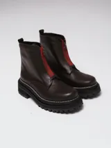 Botinetas de cuero negro con diseño combinado en gamuza y cuero texturizado. Presentan cierre frontal central, suela track dentada con costuras visibles en contraste y caña media.