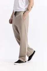 Pantalón de algodón de corte recto y estilo relajado, color beige. Cuenta con cintura elástica con cordón de ajuste, bolsillos laterales y logo de la marca estampado discretamente en el frente.