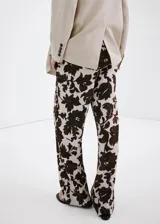 Pantalón largo de corte recto y tejido fluido, con diseño estampado floral en tonos marrón y crudo, bolsillos laterales y cierre oculto.
