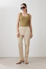 Pantalón de corte recto en color beige, con cintura media y cierre frontal oculto.