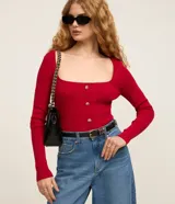 Blusa cropped de punto rojo, de manga larga y escote cuadrado. Cuenta con botones dorados decorativos en la parte frontal.