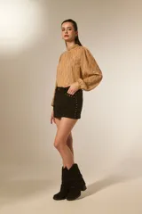 Minifalda negra de poliéster con corte al cuerpo, tiro alto y detalle de tachas doradas decorativas a lo largo de la costura lateral y el bolsillo delantero.