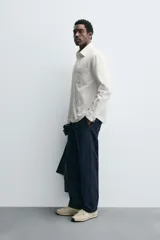 Camisa de corte relajado confeccionada en algodón, con cuello solapa, manga larga con puños abotonados, bolsillo de plastrón en el pecho y cierre frontal con botones.