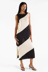 Vestido midi tejido bicolor en negro y beige con brillo sutil, escote bote, diseño sin mangas y abertura lateral en el dobladillo.