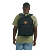 Mochila Jansport modelo Main Campus, color negro, con compartimento principal con cierre, bolsillo frontal con cierre y bolsillo lateral de malla para botella. Presenta un parche de cuero marrón con dos remaches en el bolsillo frontal.