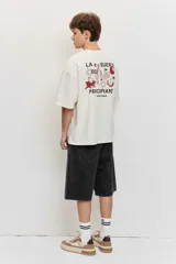 Remera marrón oversize de manga corta, con cuello redondo y pequeños estampados blancos en el pecho.