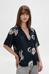 Camisa de algodón con estampado en tonos claros sobre base azul oscura, cuello solapa, mangas cortas y cierre frontal con botones.
