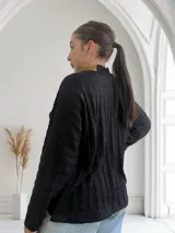 Polera negra de tejido trenzado con cuello alto y bolsillo de cuero color camel.