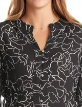 Blusa de gasa estampada con flores blancas sobre fondo negro, marca Zac & Rachel. Presenta cuello a la base, escote en V con abertura de botones y mangas 3/4 amplias. Los laterales tienen lazo.