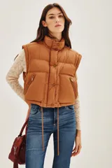 Campera puffer color tostado, con cierre frontal y botones a presión, cuello alto y puños tejidos acanalados.
