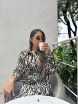 Camisa con estampado de cebra, de corte amplio y fluido, con cuello camisero y cierre frontal con botones.