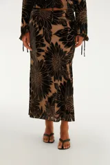 Falda midi de corte fluido y silueta evasé, confeccionada en tejido devoré transparente color tostado con un llamativo estampado de grandes flores negras en terciopelo. Cuenta con cintura elástica.
