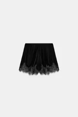 Bermuda de tiro alto confeccionada en terciopelo negro, con cintura elástica y bajo decorado con aplicación de encaje a tono.