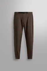Pantalón de hombre color marrón oscuro, corte regular fit, confeccionado en tejido técnico compacto elástico. Presenta cintura ajustable con cinturón negro a contraste, bolsillos frontales, bolsillo trasero con cierre y bolsillo cargo con cierre en la pernera.