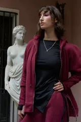 Campera deportiva oversize color bordó con capucha, cierre metálico frontal y mangas raglán de volumen pronunciado. Cuenta con puños largos de rib elástico y cordones regulables a tono con terminaciones metálicas.