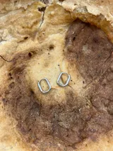 Par de aros plateados con forma de argolla rectangular.