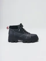 Bota acordonada de estilo montañés con suela track de goma robusta. Confeccionada en cuero con detalles de gamuza en la talonera y tirador trasero. Presenta costuras a contratono y cordones bicolores.