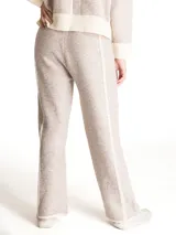 Pantalon de punto color beige con textura jaspeada, corte recto y holgado. Presenta cintura elastizada con cordón de ajuste y detalles de costuras verticales en color crema a lo largo de las piernas.