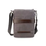 Morral de tela canvas gris con detalles en cuero sintético marrón. Cuenta con solapa frontal con cierre magnético, bolsillo tipo guantera bajo la solapa, división interna desmontable con velcro y correa larga regulable.