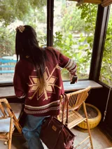 Cardigan tejido artesanalmente en lana color crudo, con diseño de copo de nieve en la espalda y bordados a mano.