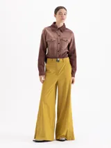 Pantalón de corte ancho y silueta relajada, confeccionado en tejido técnico con elasticidad. Presenta recortes verticales en el frente que terminan en aberturas en el ruedo y cuenta con un cinturón integrado con hebilla metálica de enganche.