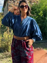 Camisa de tencel en tono azul denim, con cuello mao, cierre frontal de botones y mangas largas abullonadas. Presenta un canesú con detalle de bordado sutil en el mismo tono.