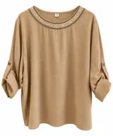Blusa de manga larga color tostado con cuello redondo, detalle de bordado geométrico en el cuello y tiras con botón para ajustar las mangas.