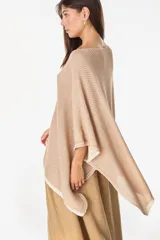 Blusa de punto estilo poncho en color beige, con diseño amplio, cuello redondo y aplique de etiqueta con el logo de la marca en el borde inferior.