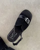 Sandalias marrones con tiras anchas de tela y cuero sintético, hebilla metálica y suela plana.