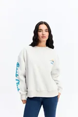 Buzo de algodón color marrón chocolate, con cuello redondo y diseño holgado. Presenta una estampa gráfica en la espalda con motivos de atardecer y montañas, junto con texto decorativo. Además, incluye una estampa en la manga con letras grandes.