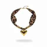 Collar con pañuelo de tela estampado animal print, decorado con esferas metálicas doradas y un dije central de corazón en acero dorado. Incluye cadena de ajuste metálica.