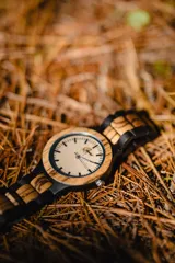 Reloj de pulsera con caja y esfera de madera clara, malla de madera oscura con incrustaciones de madera clara.