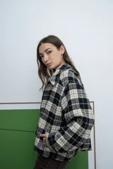 Chaqueta de corte recto con cierre frontal, cuello camisero y diseño a cuadros en tonos negro y beige.