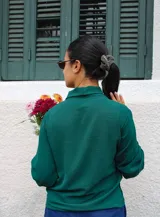 Blusa verde de manga larga con cuello tipo lazo, confeccionada en tela con textura ligera y corte recto.