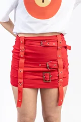 Minifalda roja con tres cinturones horizontales con hebillas metálicas y tiras verticales con ojales.