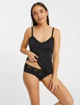 Musculosa íntima tipo viso, color negro, confeccionada en microfibra con tacto sedoso. Presenta escote en V con detalle de malla, tirantes regulables y propiedad antiestática.