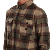 Camisa de franela a cuadros en tonos marrón, verde y beige, de manga larga con dos bolsillos en el pecho.